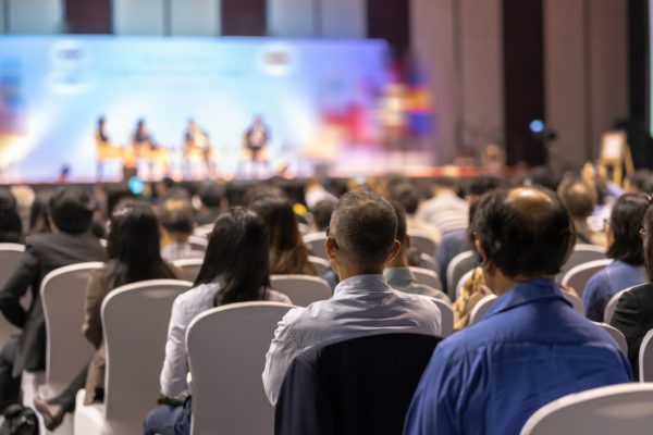 Business Opportunities Offered - Rear view of Audience listening Speakers on the stage in the con